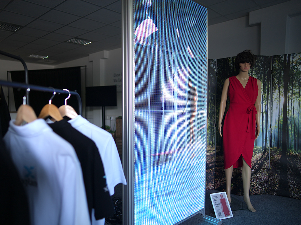 Transparente LED Wand mit hoher Leuchtkraft hinter Glasfront bei Tageslicht.